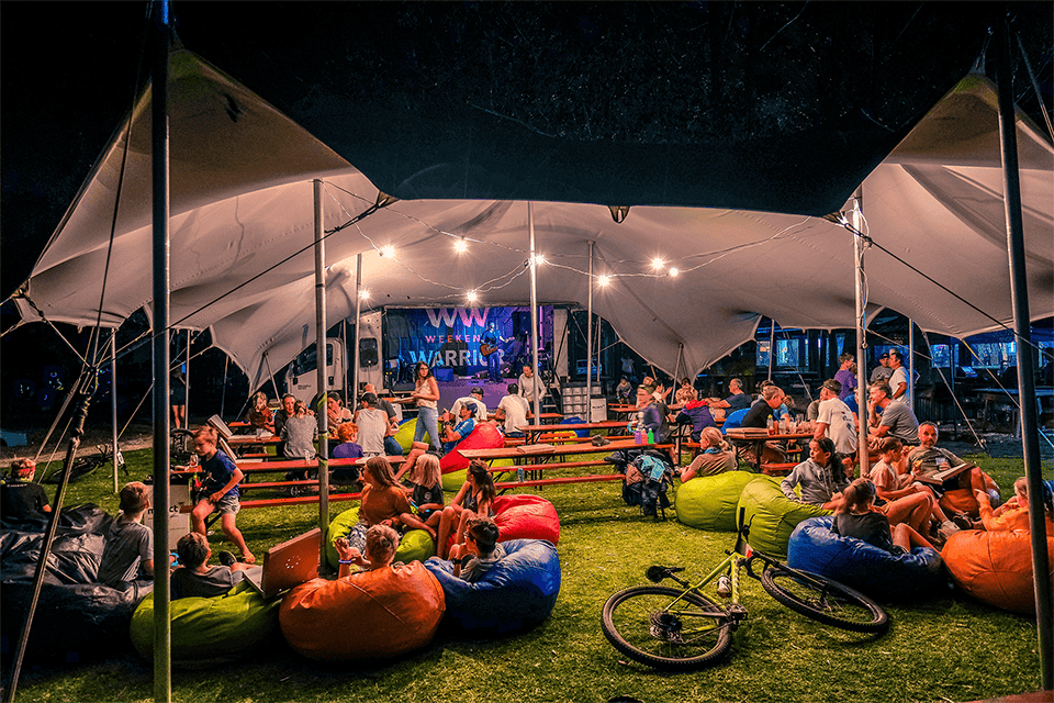 A Bedouin stretch tent lit with festoon lights at night, with beer benches and bean bags for guests at a Red Cherry event in South Africa